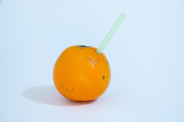 Orange with a straw inserted as in a drinking glass photographed on a white background.