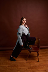 Independent young woman posing in the photostudio. Gorgeous young female in classic suit and grey coat.