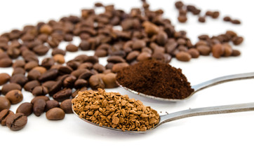 two spoons of different coffee on a background of coffee beans. White background. Close-up. Ground and instant coffee in spoons.