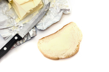 slice of long loaf with butter and knife on a white background.