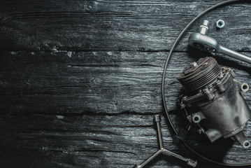 Old car air conditioning compressor on the black wooden workbench background.