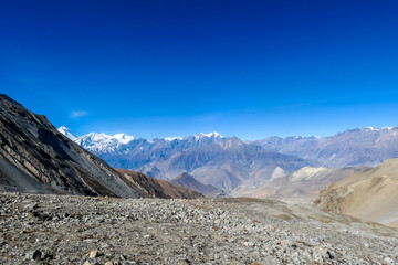 A panoramic view on dry Himalayan valley, located in Mustang region, Annapurna Circuit Trek in Nepal. In the back there is snow capped Dhaulagiri I. Barren and steep slopes. Harsh condition.