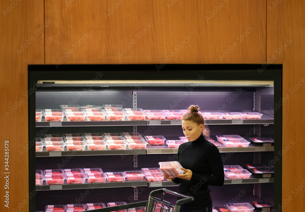 Wall mural woman purchasing a packet of meat at the supermarket