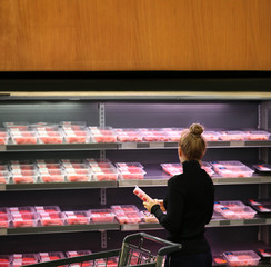 Woman purchasing a packet of meat at the supermarket	