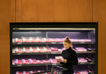 Woman purchasing a packet of meat at the supermarket	