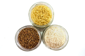rice, buckwheat and pasta in glass jars on white. View from above.