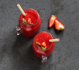 Fototapeta na wymiar Strawberry drink in a jar with a bamboo straw on a dark gray background top view