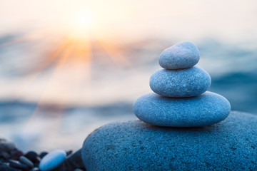 rock pebble pyramid, zen stones on sea beach, morning sunrise, meditation, spa, harmony, calm background, balance concept, copy space