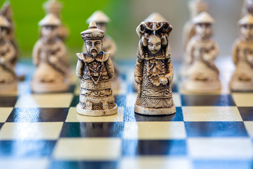 Close-up of a the white king and queen chess piece sitting on a chessboard