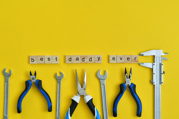 Inscription Fathers Day with different tools on yellow background. Wooden letter BEST DADDY EVER....
