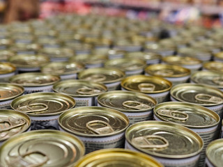 Iron cans with canned goods in a store on the counter. A lot of goods in the supermarket