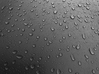 Drops of water on a black metal surface, beautiful background after rain