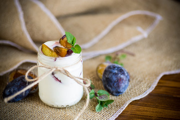 Homemade sweet yogurt with slices of ripe plums in a glass