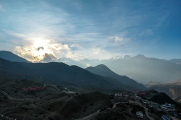 A setting sun in Nepalese Himalayas, Muktinath, Annapurna Circuit Trek. The sun sets behind high mountains. The mountains are covered with dark shadows. Freedom and adventure. Day break.
