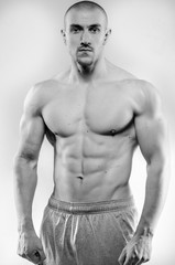 Naklejka premium Sporty guy posing in the Studio on the background. Sports, beauty, black and white photography
