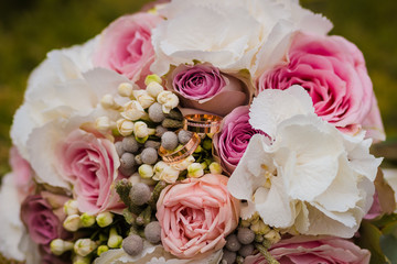 Wedding bouquet and wedding rings lying on grass.