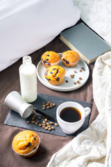black tray with cup of coffee and milk on the bed with muffins cake for breakfast. stay home safe at quarantine concept