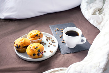 cup mug of coffee espresso on the bed with blueberry muffins on tray plate for breakfast. stay home safe concept with copy space, flatlay