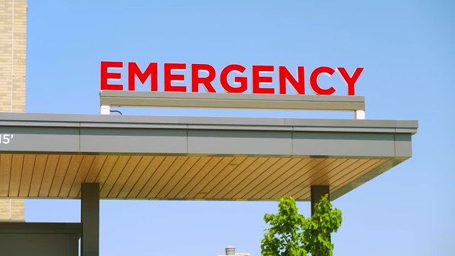 Establishing shot of Emergency sign outside during the day on a hospital medical building for the ER / emergency room entrance area