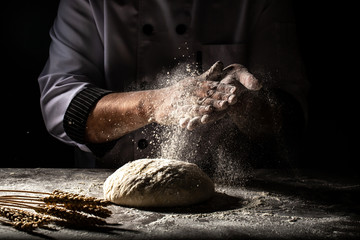 Photo of flour and men hands with flour splash. Cooking bread. Kneading the Dough. Isolated on dark...