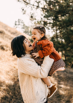 Mother and daughter playing outside on a sunny day. Mother hugging child, having fun together.