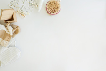 A beauty composition with copy space: cute flowers, a towel, cream and lip balm on a white background. 
