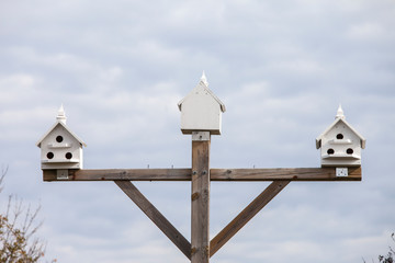 Three white bird houses on a pole.