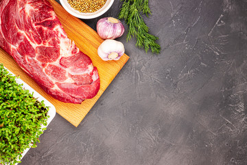 fresh raw beef with vegetables and microgreen on a black marble background, top view