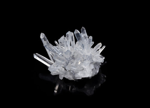 macro shot of a raw clear crystal quartz specimen on a black reflective background