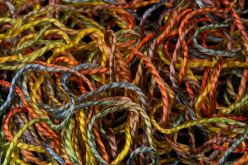 macro shot of variegated pure silk embroidery thread tangled in a pile. Very colorful with warm...