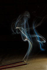 Puffs of smoke from a candle against a dark background