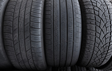 a row of used tires with three different tread types, left to right, directional asymmetrical for all weather, symmetrical mostly for passenger cars, and asymmetrical mostly for sports cars. 