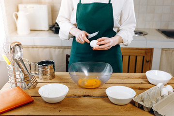 Close up woman's hands break the egg in a bowl for dough. Home cooking concept