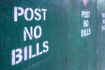 post no bills spray painted text letters on closed off unrban contrustion area