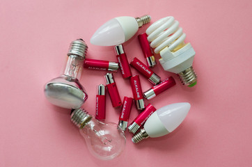 a lot of pink colored batteries and different type of light bulbs are ready for recycling on a pink...