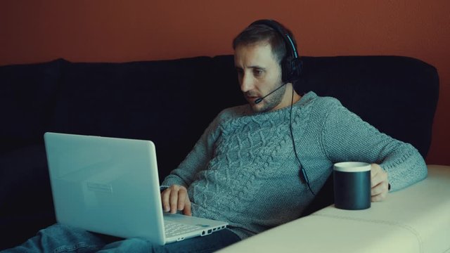 Hermoso joven trabajando en una computadora port&aacute;til mientras est&aacute; sentado en la sala de estar escribiendo durante la cuarentena debido al virus covid-19