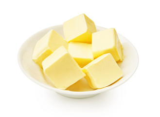 Butter pieces in white bowl isolated. Butter cubes.