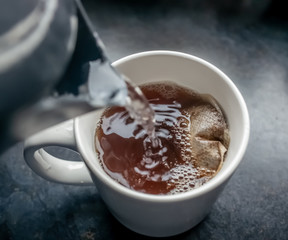  Pouring boiling water in to a mug containing a one-cup teabag whilst making a drink of English tea