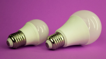 two white light bulbs of different sizes on a purple background