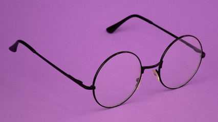 black round glasses on a purple background