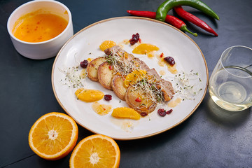 Fried potatoes with beef, sprouts and orange sauce with a glass of white wine on a wooden table