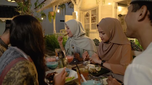 muslim breaking the fast together. friend and family sitting together enjoy iftar dinner