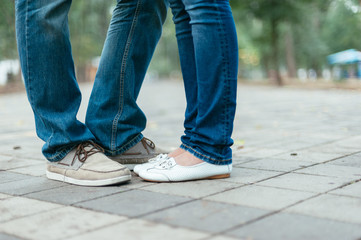 two pairs of feet of a romantic couple on a sidewalk tile