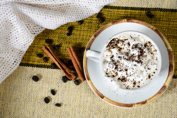cup of coffee with milk and whipped cream on the table with roasted coffee beans