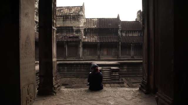 Mujer leyendo sentada en los templos de Angkor Wat