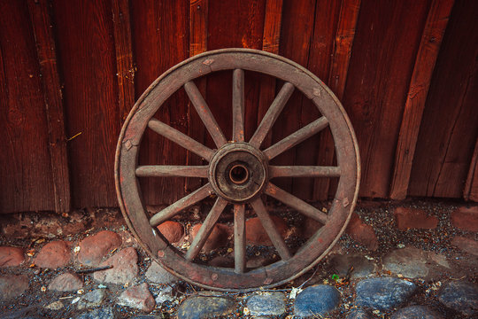This photo shows a closeup of old wooden wheel in the village.