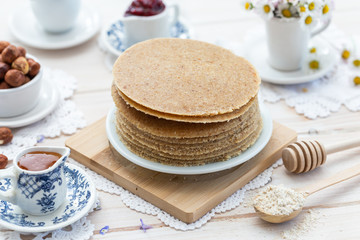 Home made raw vegan pancakes on a white table. Healthy morning meal on a wooden plate.