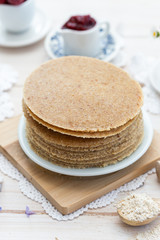 Fototapeta na wymiar Home made raw vegan pancakes on a white table. Healthy morning meal on a wooden plate.