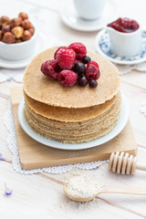 Raw vegan pancakes on a wooden plate with raspberries on top. Healthy eating lifestyle.