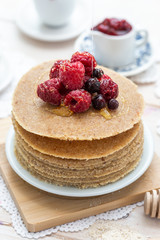 Raw vegan pancakes on a wooden plate with raspberries on top. Healthy eating lifestyle.